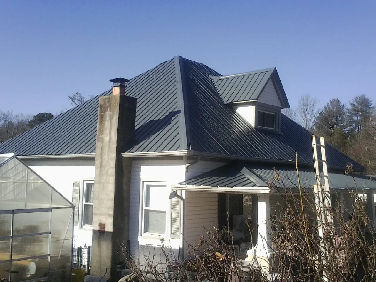 Dark blue standing seam metal roof on a white farmhouse with dormer — Slate & Tile Roof Repair by Roofing Brothers in Ash