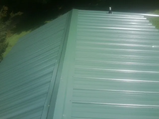 New green metal panels meeting at the ridge of a roof — Flat Roof Repair work by our crew in Ash
