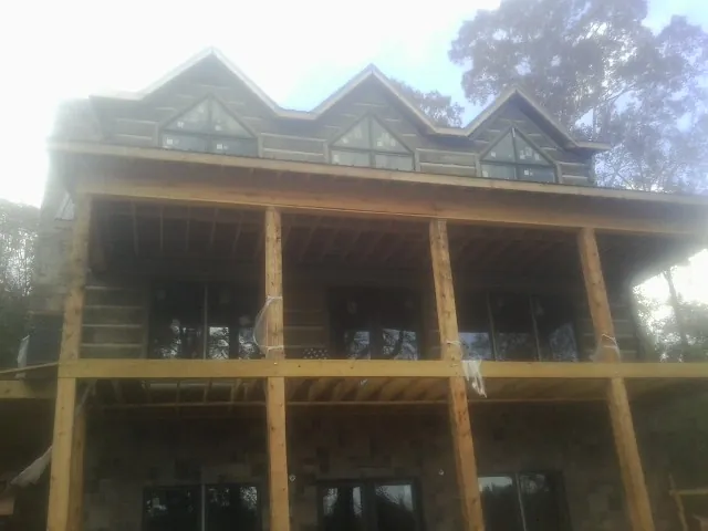 Dormers and porch framing on a large log home under construction — Roof Coating work by our crew in Ash